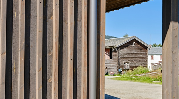 Detaljfoto av kledning i MøreRoyal grå, Skårvold Gård. Stabbur i bakgrunnen.